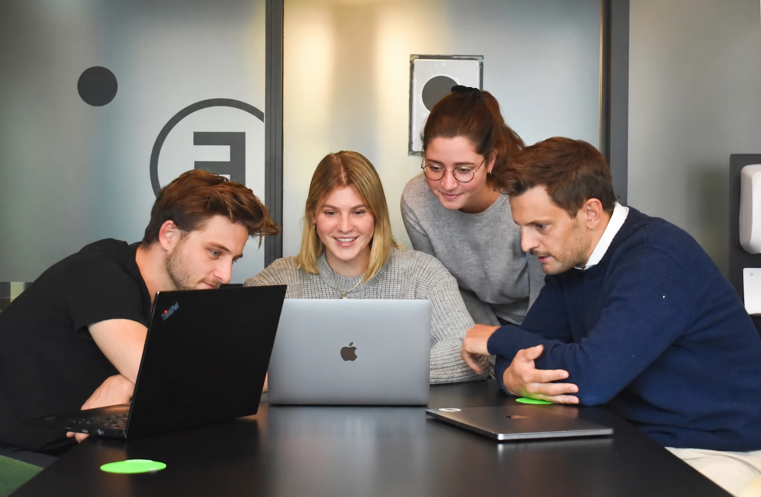 Aventis Digital software team collaborating around laptops in a modern office